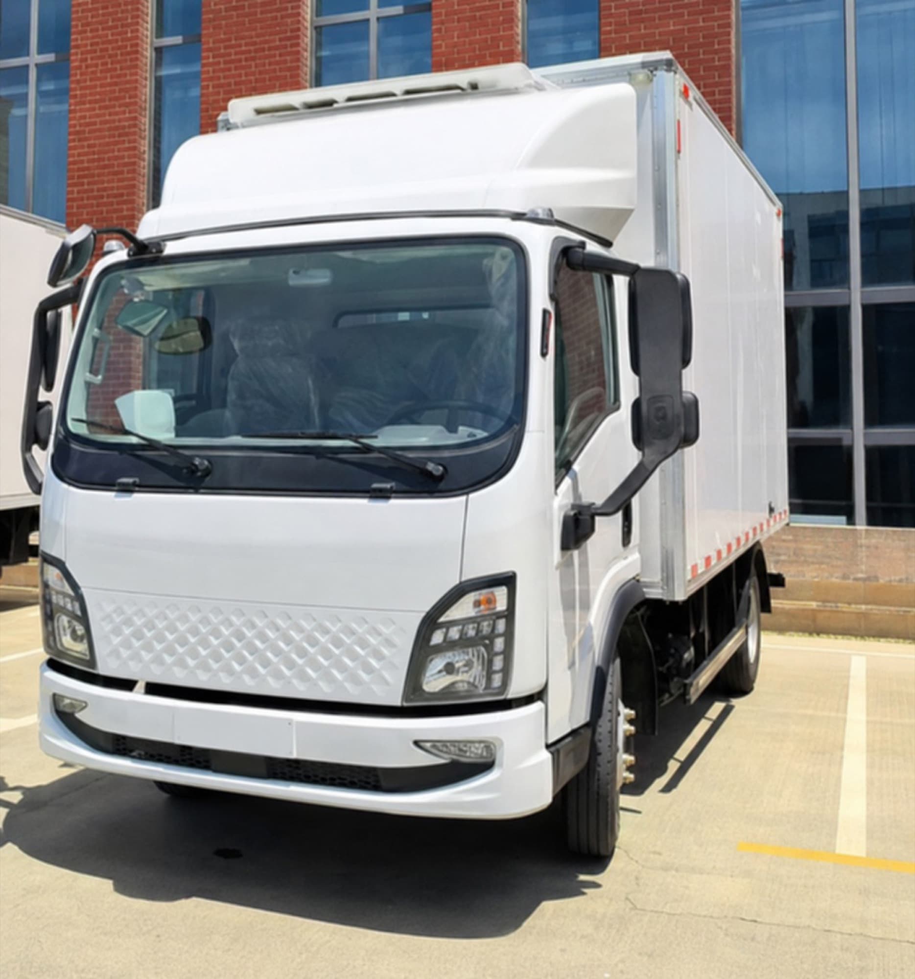 White electric box truck parked in front of a commercial building